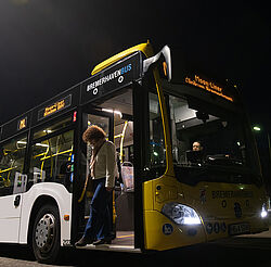 Eine Frau steigt nachts vorne aus einem Bus
